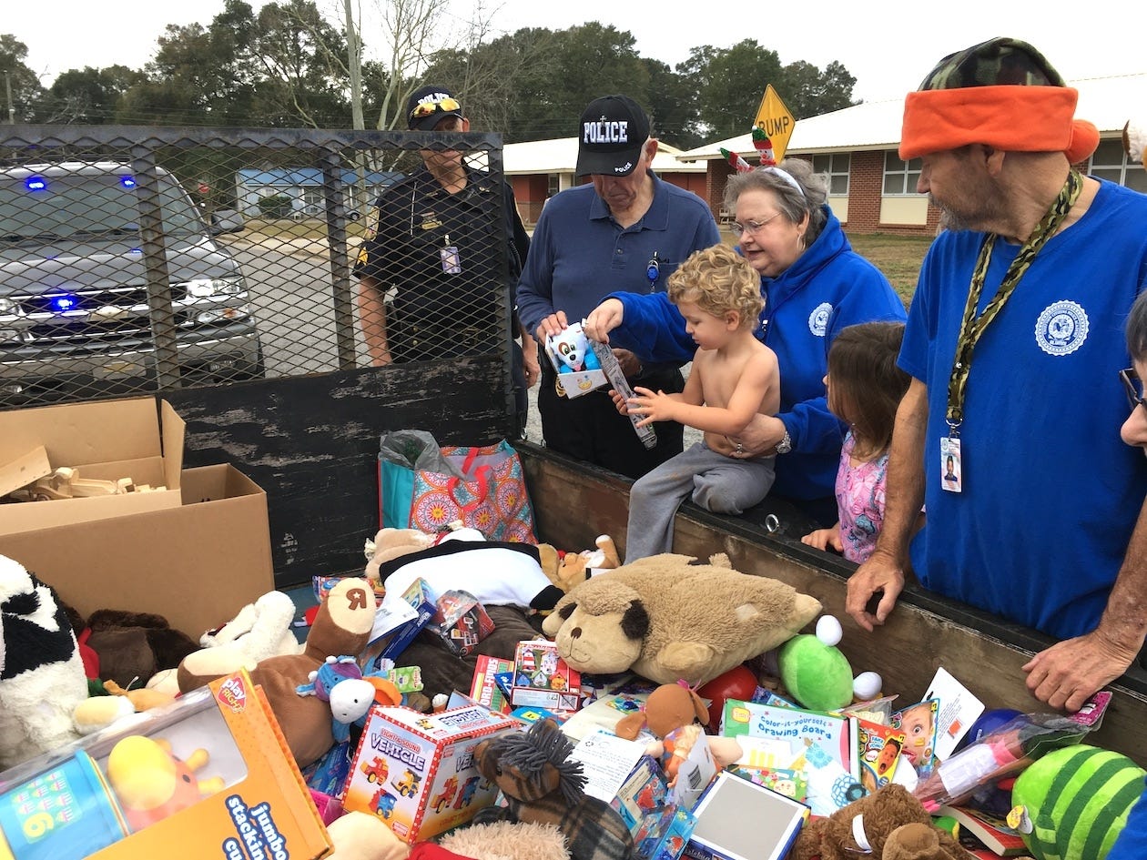 Crestview Citizens Police Academy Alumni member Dianne Tomlin helps children select a Christmas present during the Police Department’s annual Toy Run. Auxiliary officer Sgt. Al Humphrey, police chaplain the Rev. Harry Tomlin and CCPAA member Tom Underwood observe during the Dec. 23 toy handout. [BRIAN HUGHES | Crestview Police Department]