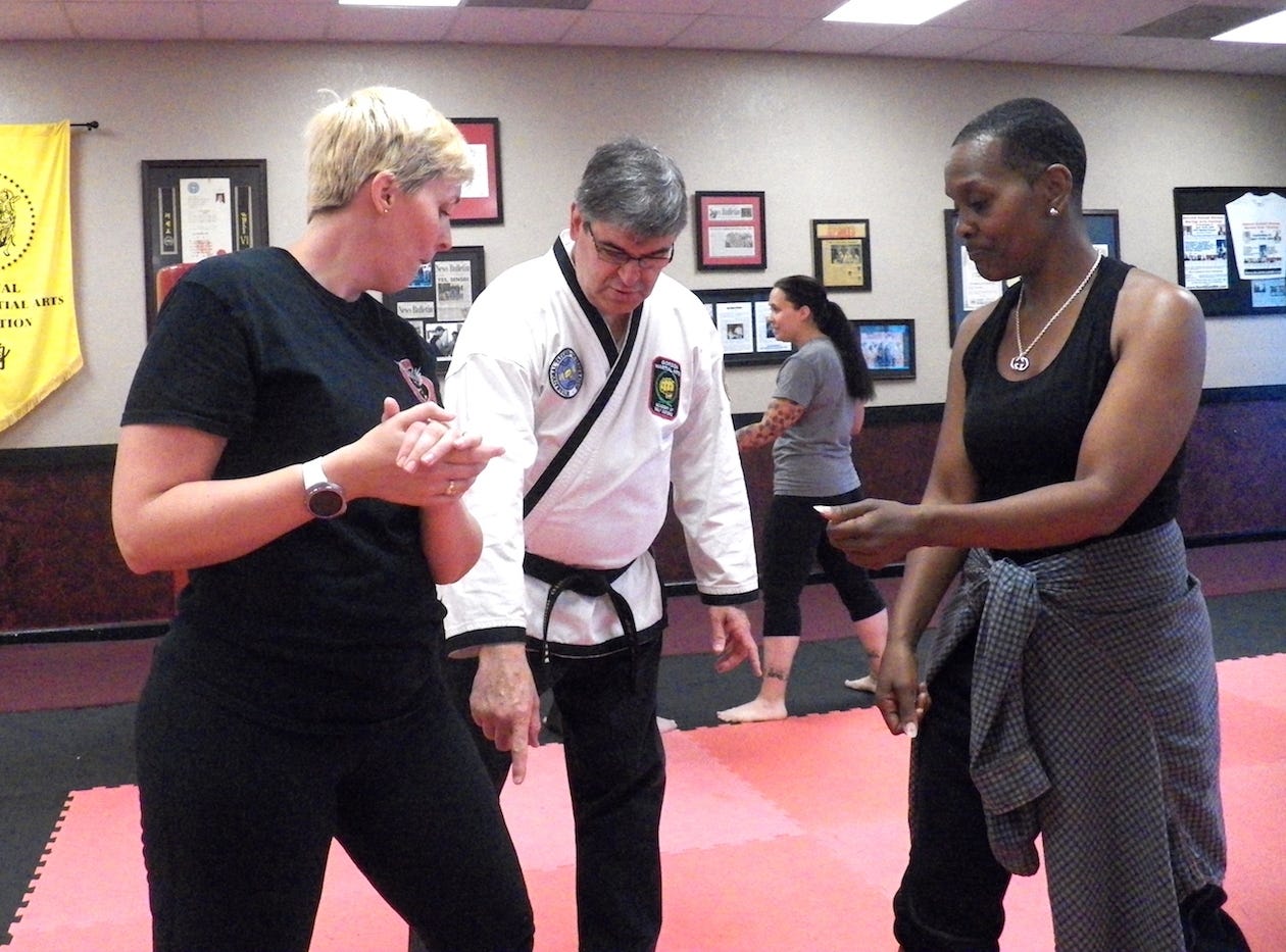 As women’s self-defense course participants practice techniques, Gordon Martial Arts volunteer Dr. Alberto Barbon offers pointers. [PHOTO COURTESY OF GORDON MARTIAL ARTS]