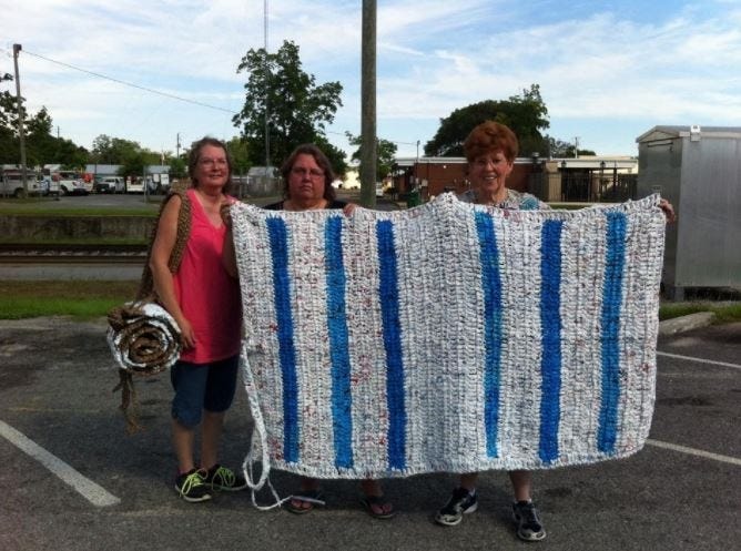 The Emerald Coast Bag Ladies — whose members are pictured after creating a mat for the homeless in 2017 — seek volunteers. [File photo]