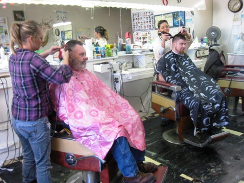 Barbers Kristen Phillips and Nina Roberts cut Keith Brooks and Josh Miller's hair at Leon's Barbershop, which closes today after 60 years on Main Street in Crestview.