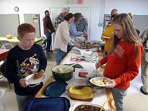 John Riley, 9, and Lacey Miller, a Laurel Hill School eighth-grader, work their ways down the bounteous supper table.