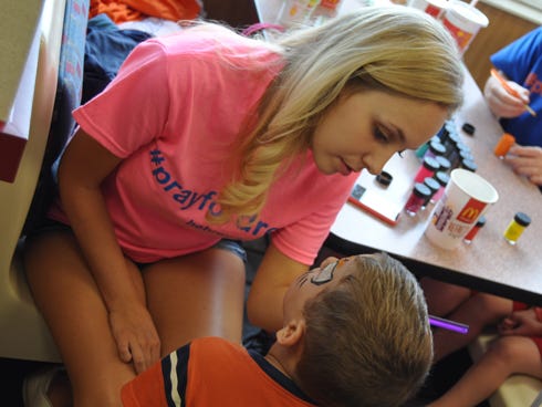 Moriah Brannon paints on the face of 3-year-old Aiden Gabriel during the fundraising event for Drew Barefield on Monday night at the McDonald’s restaurant on North Ferdon Boulevard. Brannon was one of several Emmanuel Baptist Church youth members to help customers during a fundraising event.