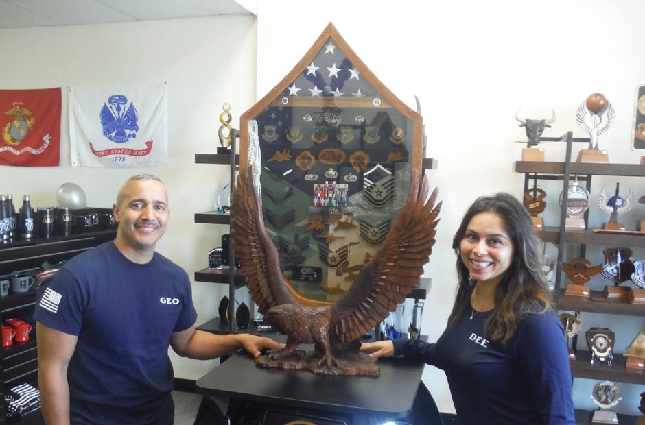 George and Daisy Lebron pose with George's custom shadow box that he crafted for himself. Their new business, DaGeo Art, is located at 767 N Ferdon Blvd in Crestview. [AARON JACOBS | NEWS BULLETIN]
