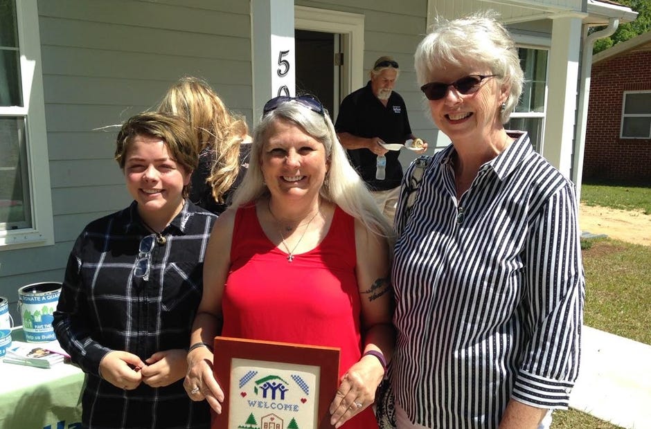 Barbara Harrison, right, of the Sand Dunes Chapter of the Embroiderers Guild of America, presents a welcome sampler to Lorraine Karagiannes and her granddaughter, Sariya, at the dedication of their new Habitat for Humanity home in May in Crestview. EGA member Kimberly Mortimer stitched the sampler, and EGA member Cynthia Hardesty framed it. Members meet from 1:30 to 4:30 p.m. fourth Sundays at The Holy Name of Jesus Catholic church in Niceville.  [SPECIAL TO THE NEWS BULLETIN]