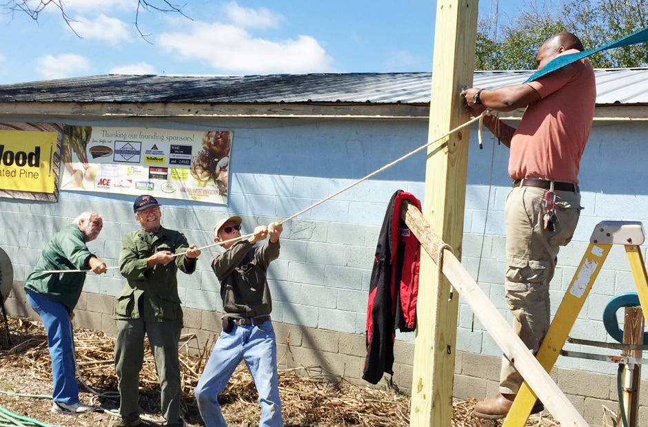 A team of Common Ground Community Garden volunteers led by John Bouton mounts one of the garden's shade sails in March. Assisting Bouton are Bob Benson, Joe Phelps and Tray Shuford.