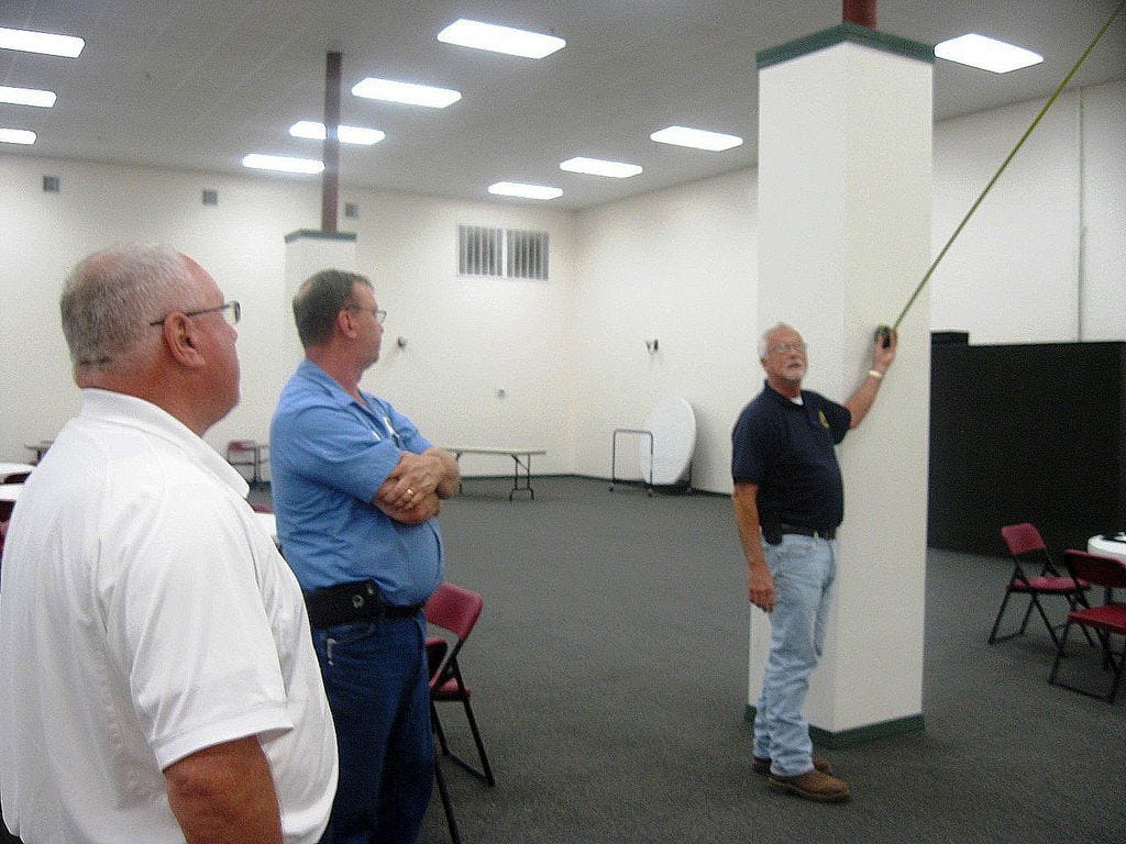 Crestview Public Works Director Wayne Steele, facilities manager Stan McKenzie and assistant director Chuck Powell discuss how a display of 12 service branch and historical flags will be hung in Warriors Hall.