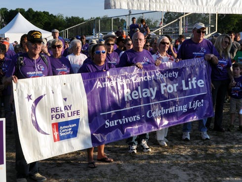 Cancer survivors carry a banner before walking a ceremonial first lap during last weekend's Relay for Life at Old Spanish Trail Park.