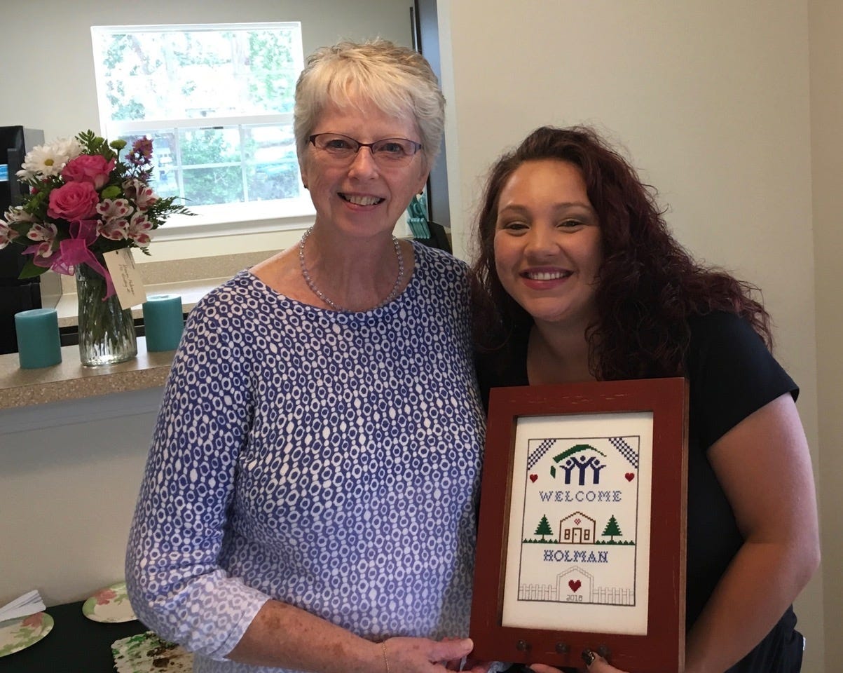 Barbara Harrison, left, with the Sand Dunes Chapter of the Embroiderers’ Guild of America, presents a Habitat for Humanity Welcome Sampler to Shawna Holman and her three daughters at the dedication of her new home in Crestview. [CONTRIBUTED PHOTO]