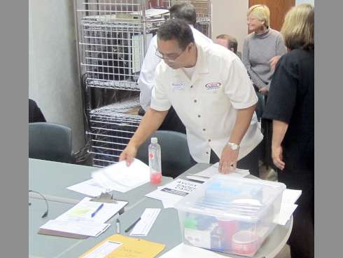 Supervisor of Elections staff member Ray Bolden checks paperwork as the canvassing board behind him observes incoming results on election night.