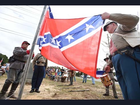 Confederate Civil War re-enactors raise the Confederate flag at a new site for the William “Bill” Lundy Memorial on Saturday on private property. The Crestview city council voted to have the flag removed from the previous site which was on public property. Lundy relatives celebrated the new site on Saturday during a ceremony.