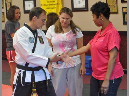 Martial arts instructor Greg Bledsoe shows Samantha Torgerson and Alicia Booker some moves during a free women's self-defense course on Saturday at Gordon Martian Arts.