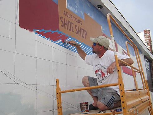 Artist Darryl Davis paints a mural depicting historic Crestview on the side of a 1920s Main Street building.