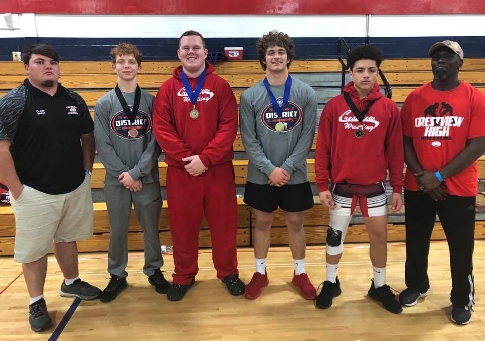 Wrestlers Karter Watson, Weston Tew, Kenard Madden, and Malachi Santiago pose with their coaches after placing at the district tournament. [CONTRIBUTED PHOTO]