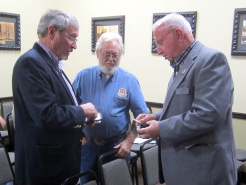 Crestview City Councilman Joe Blocker, right, exchanges business cards with representatives of Confederate heritage organizations prior to Monday's council meeting, at which the issue of the Confederate battle flag over the Uncle Bill Lundy memorial was raised.