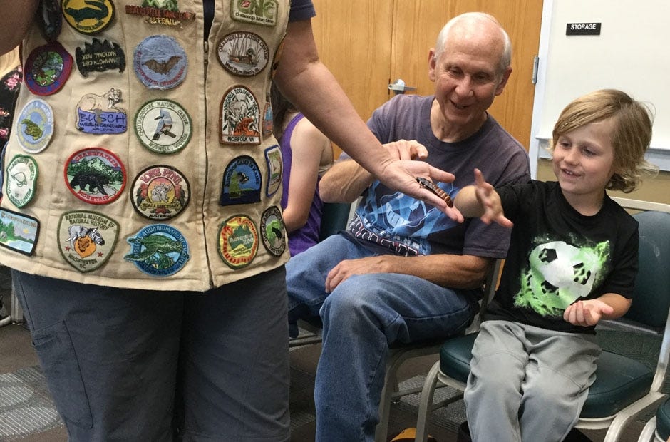 Robert Johnson, of Gulf Breeze, and Davey Heacock, 4, of Crestview, pet a Madagascar cockroach during a Nonie's Ark Animal Encounter April 26 at the Crestview Public Library. [Special to the News Bulletin]