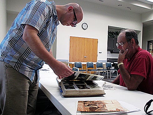 Pediment Publishing technician Jon Shields selects photos from James E. Cain’s family photo album for the county centennial book.