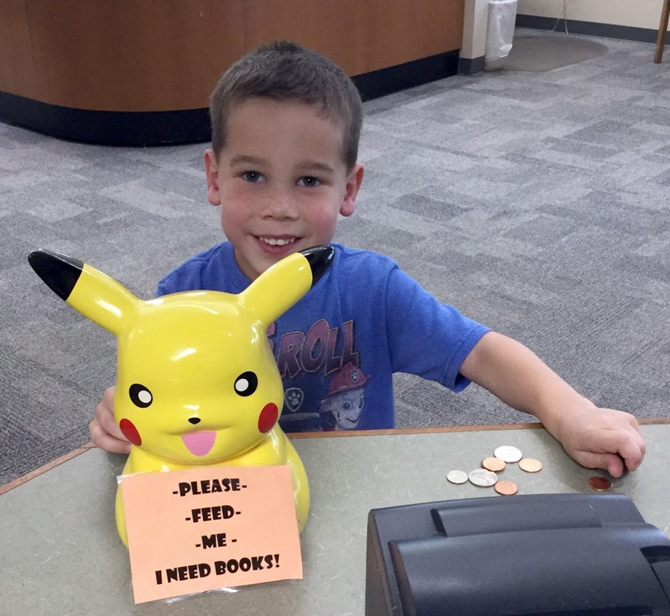 Matthew Logan, age 5, of Holt, cheerfully donates change during a recent visit to the Crestview Public Library.