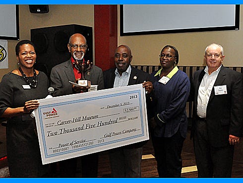 Bentina Terry, Gulf Power vice president of External Affairs and Corporate Services, left, and Ed Taylor, the utility's Fort Walton Beach district manager, far right, present a $2,500 check to George Stakley and Carver-Hill Museum board members during a Dec. 6 ceremony.