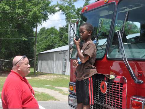 Capt. Jody Smallwood of the Crestview Fire Department instructs Jayden Teague, 10, to send a command to dispatch. Firefighters, who visited Jayden and 27 other children at Mt. Zion AME Church's Vacation Bible School, taught children about the department’s life-saving equipment.