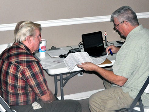 Richard Masters, of CIL Disability Resource Center, right, completes paperwork for Clifford Bean during Thursday’s Shady Grove Helping Hands Community Fair at the Shady Grove Assembly of God Church. Bean received a free landline telephone specialized for the hearing-impaired.