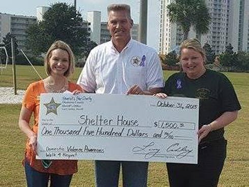 Okaloosa County Sheriff Larry Ashley, center, and investigator G. Kaye Towner, right, present a $1,500 check to Shelter House executive director Rosalyn Iovieno.
