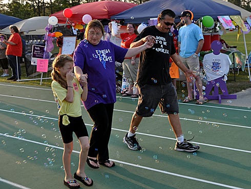 Caitlyn Dill, 9, walks with her grandparents, Gloria and Alex Garcia, Friday during the Relay For Life survivors and caregivers walk at Shoal River Middle School.