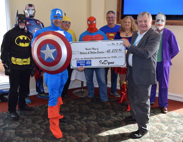 InDyne Program Director Mike Guidry, dressed as Captain America, presents a $42,275.91 check to Ken Hinrichs, United Way of Okaloosa-Walton Counties' CEO, as other InDyne department heads look on.