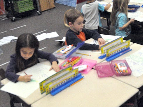 Ava Adams, 6, left, and Logan Ward, 5, design and decorate place mats along with their classmates in Carol Hansford's kindergarten class Wednesday at Baker School. Students are preparing for a Dec. 4 senior citizens banquet at the school.