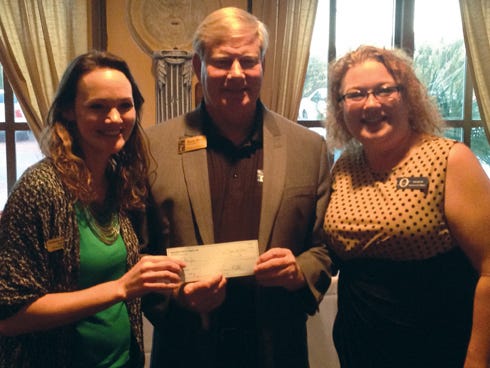 Amy Baty, the Okaloosa Arts Alliance's executive director, left, and OAA President Kerri Woods present an $800 check for art education to Ken Hair, Children in Crisis president and CEO.