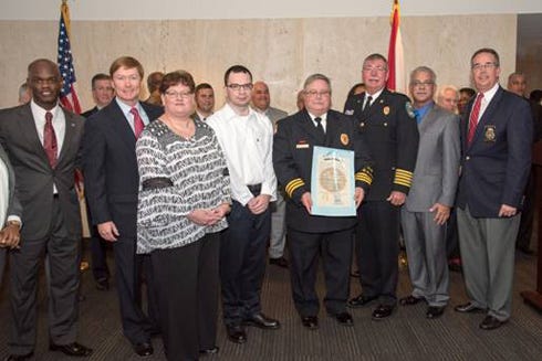 Assistant Fire Chief Ralph Everage Jr., center, is surrounded by family, colleagues, Florida Chief Financial Officer Jeff Atwater and Commissioner Adam Putnam March 1 in Tallahassee.