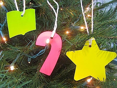Ornaments available for the library book donation fund tree include a neon book for $1, a pink candy cane for $5 or a yellow star for a $10 or more donation.