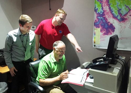 Crestview High School alumnus and Gulf Coast coordinator of the National Tsunami Hazard Mitigation Program Chayne Sparagowski reviews Santa Rosa County tsunami preparedness plans with Jason Beaman of the National Weather Service Mobile office, standing, and Brad Baker, Santa Rosa County Division of Emergency Management director.