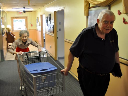 Crestview Manor resident Dennis Green helps Lexi Shelley move her shopping cart of laundry down the hallway. Green, who once was homeless, volunteers so much at the assisted living facility that he blends in with Manor staffers.