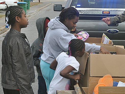 Kenya Chambers, center, searches boxes of toys for her children, Kiara, 12, and Malayshia, 6, during this morning’s Cops for Kids toy drive.