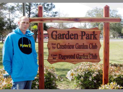 William Walton stands beside a red cedar sign he crafted for Crestview's Garden Park.