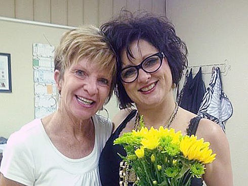 Baker School teacher Tami Black presents cosmetologist April Linton with a bouquet as a “thank you” for finding a cancerous spot on her head.