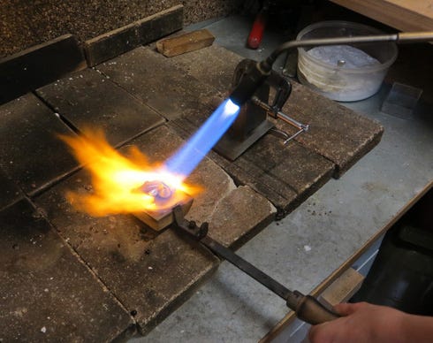 A silversmith refines a piece of silver.