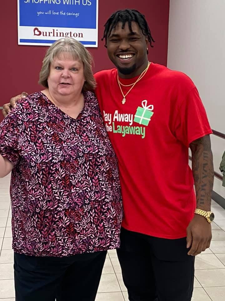 Sheila Plumley gets a picture with NFL linebacker Ulysees Gilbert III on Monday. Plumley’s sister, Sherita Graham, had a layaway of nearly $500 paid off by Gilbert on Monday. [Submitted photo]
