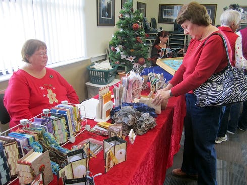 An art lover admires artist Mary Richardson’s hand-bound books and other works at the first CALA Christmas arts festival Saturday.