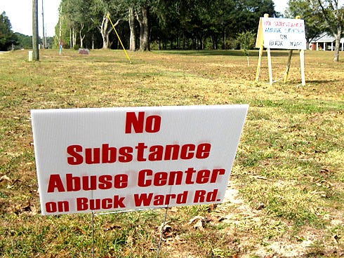 Dozens of signs protesting a substance abuse rehabilitation ministry line Buck Ward Road from Milligan to Baker.