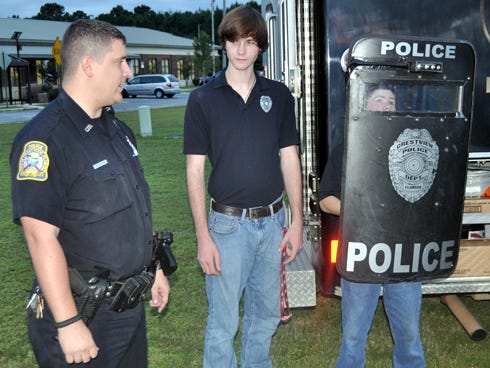 Crestview Police Officer Beau Baier speaks while Ethan Campbell, 16, listens and Timothy Lehneis, 14, holds the SWAT team shield during the National Night Out on Tuesday at the Crestview Community Center.