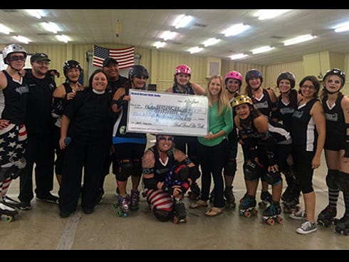 Children in Crisis Volunteer and Events Director Lauren Walls, center right, receives a $921 donation from the Beach Brawl Sk8r Dolls. The nonprofit organization will use the money to help feed and clothe Okaloosa area living at the CIC Neighborhood in Fort Walton Beach.