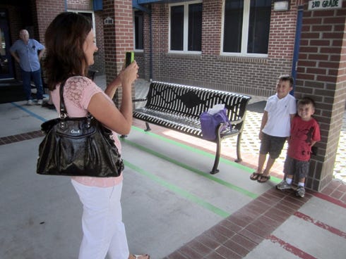 Camille Mullis uses her smart phone to photograph her sons Ricky, 7, and Jackson, 3, as Ricky prepares to begin second grade at Riverside Elementary School.