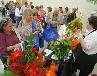 Attendees visit local sponsors’ tables prior to the cooking class, including this one staffed by Jenny Bettis, right, prior to the cooking demonstrations.