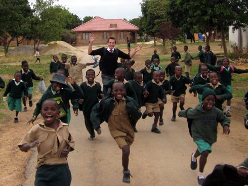 LDS Elder Justin Mozina runs with school children in Zimbabwe.