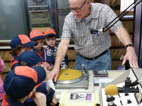 Long-time WAAZ/WJSB program host Joe Dunn describes the broadcast studio equipment's functions to visiting Tiger Scouts from Cub Scouts Pack 530.
