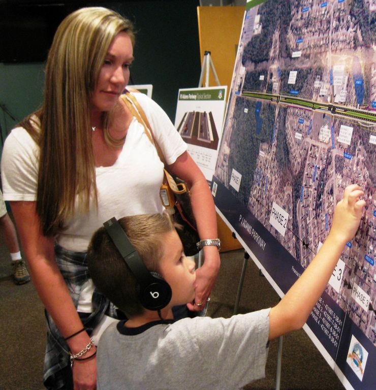 Erica Barrett and her son, Austin, 7, review plans for four-laning P.J. Adams Parkway during a Tuesday public meeting.