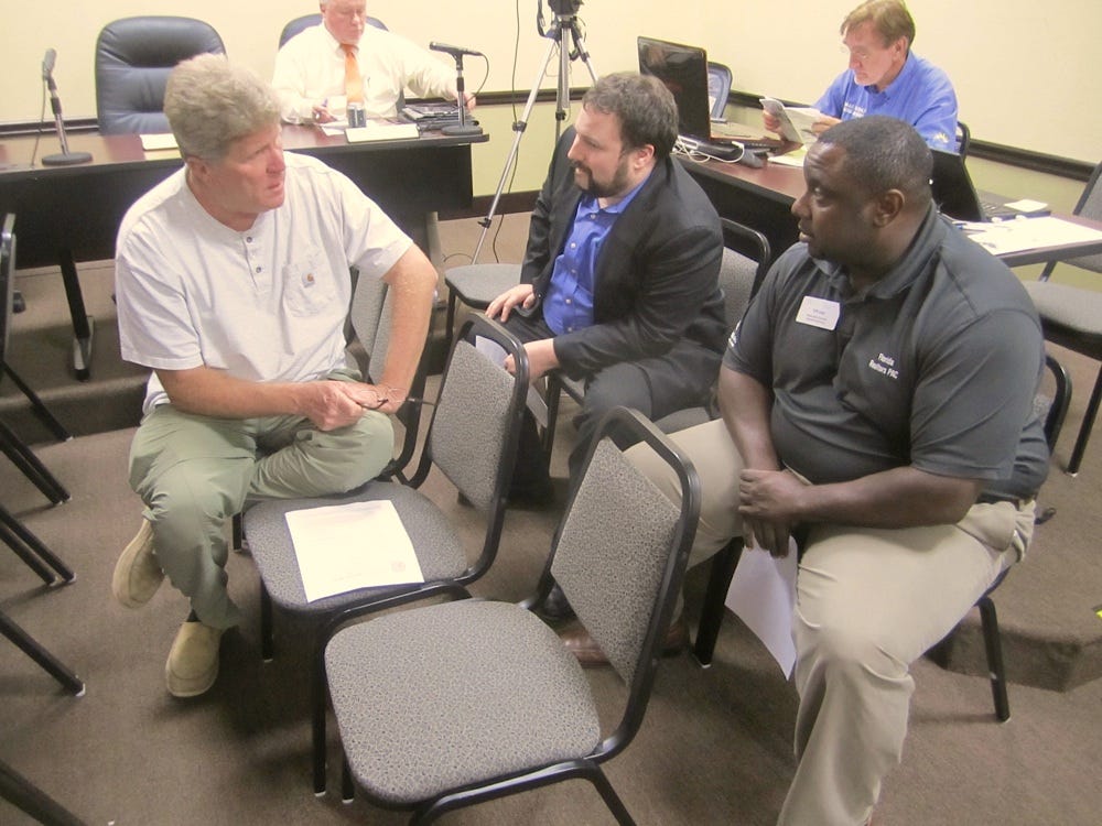 Cliff Long, of the Emerald Coast Association of Realtors, right, discusses Amendment 4 with residents prior to Monday’s city council meeting.