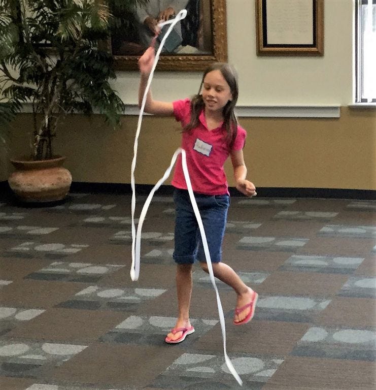 Rebecca Logan, 9, of Holt, made and danced with a ribbon in the spirit of Olympic gymnastics July 12 at the Crestview library.