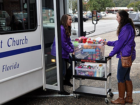First Baptist Church of Crestview Acteens members Catherine Parker and Kristen Nydereck load donations for Children In Crisis, a Fort Walton Beach nonprofit, onto a church bus.